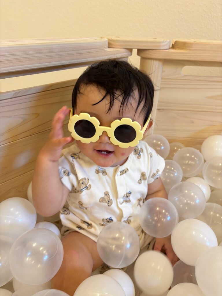 黄色のサングラスをかけてボールプールで遊ぶ赤ちゃん
